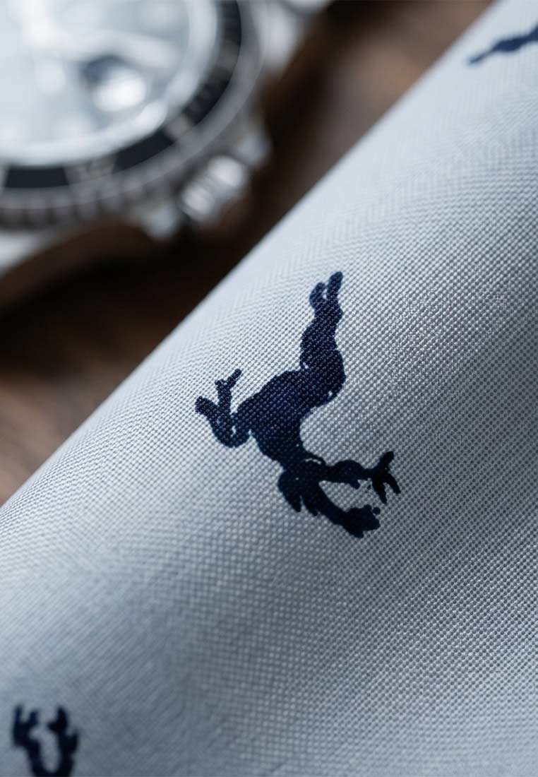 Detailansicht des Luise Steiner Stecktuchs Lois in Silber-Stein mit einem dunkelblauen Hirschmotiv auf strukturiertem Stoff.