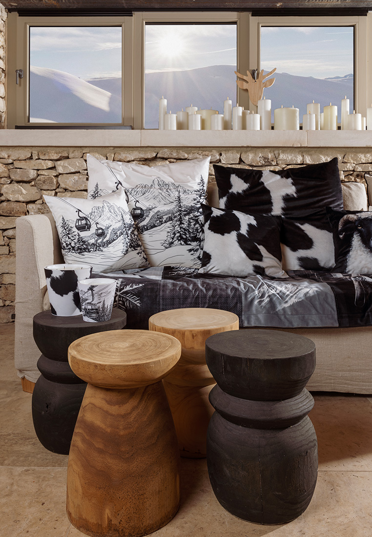 Pôdevache Chalet Chic Ambiente mit Kissen Gondelbahn und Kuhfellmotiven, Frontansicht, winterliche Wohnzimmerdeko mit alpinem Design.