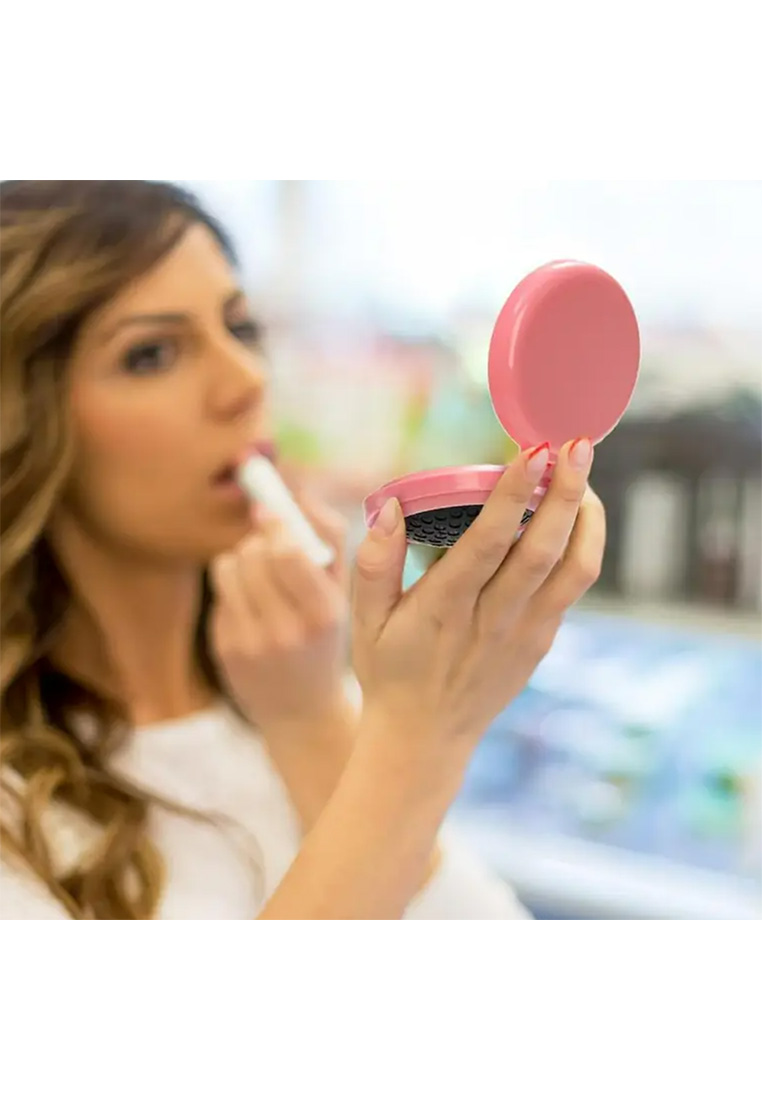 Schmuckzauber faltbare Reisehaarbürste mit Spiegel in Rosa wird von einer Frau zum Auftragen von Lippenstift benutzt, Frontansicht.