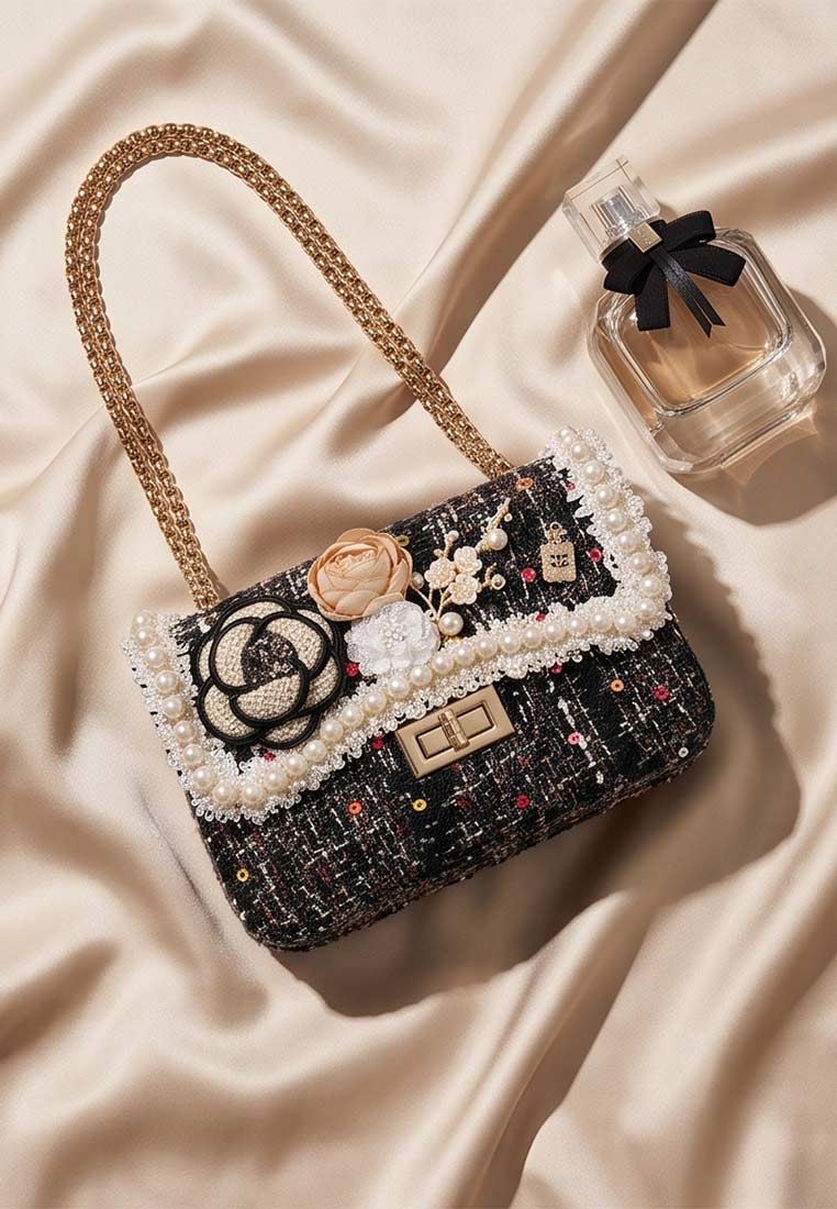Schmuckzauber Tweed Trachtentasche Glamour schwarz bunt, Frontansicht. Die Tasche ist mit Perlen und Blumenapplikationen verziert und hat eine goldfarbene Kettenschulterriemen.