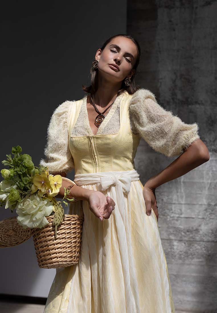 Madame Marie Dirndlbluse Kühbach gelb Frontansicht mit Puffärmeln und Reißverschluss vorne, mit Schärpe gebunden.