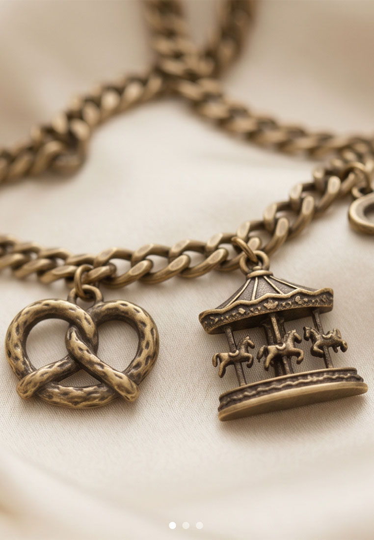 MarJo Trachten Dirndl Schürzenkette altgold mit Brezel- und Karussell-Anhänger, Nahaufnahme.