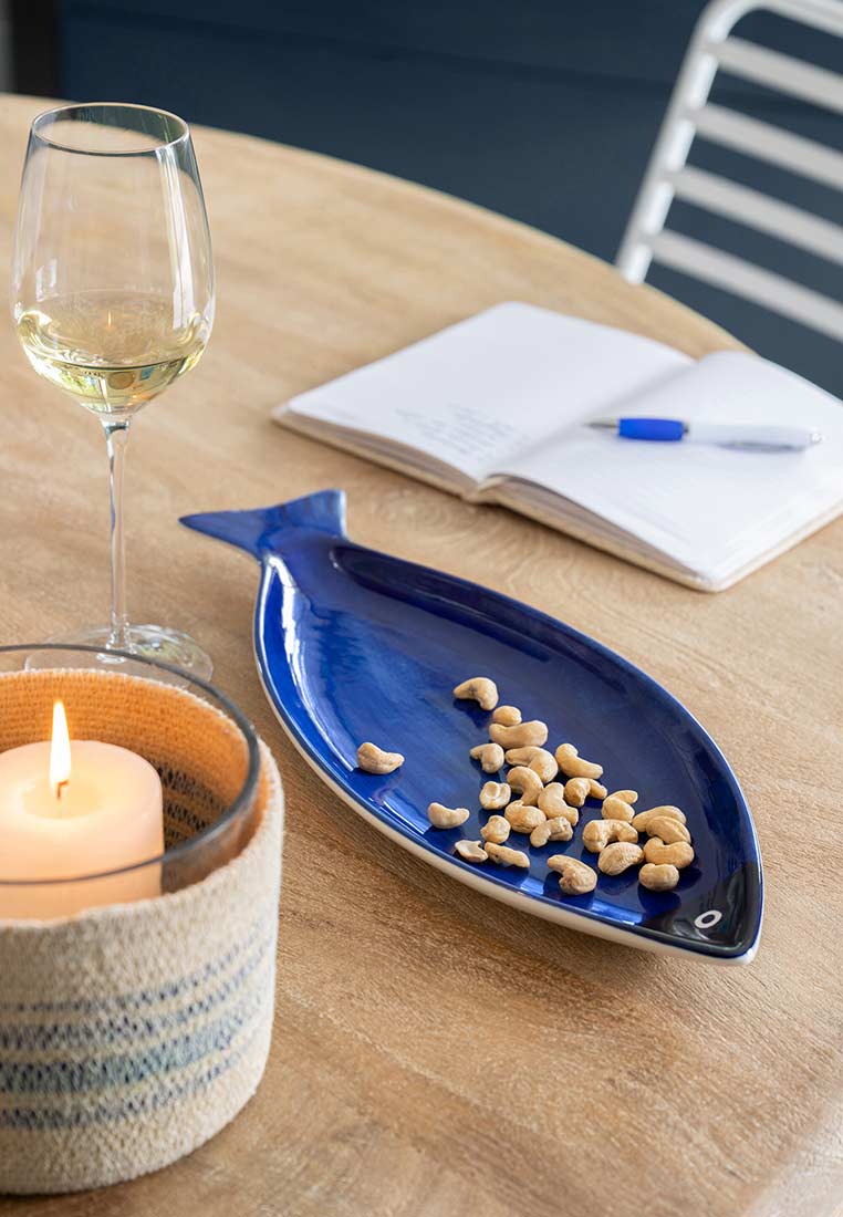 J-LINE Schale Fisch gross Blau aus glänzendem Keramik in einer eleganten, schiffsförmigen Aussparung auf einem Holztisch.