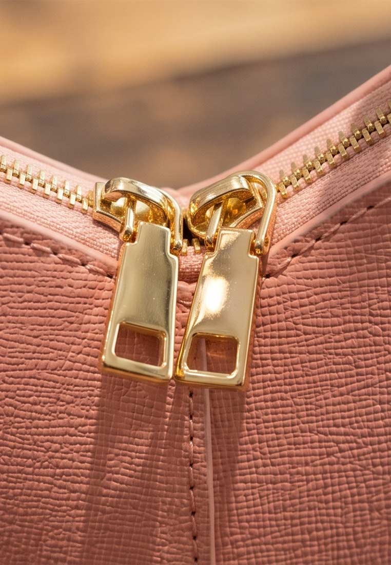 Detailaufnahme der PAN Lederwaren Trachtentasche Herzblatt in Rosa mit goldenen Reissverschlüssen. Die Tasche ist aus strukturiertem Leder.