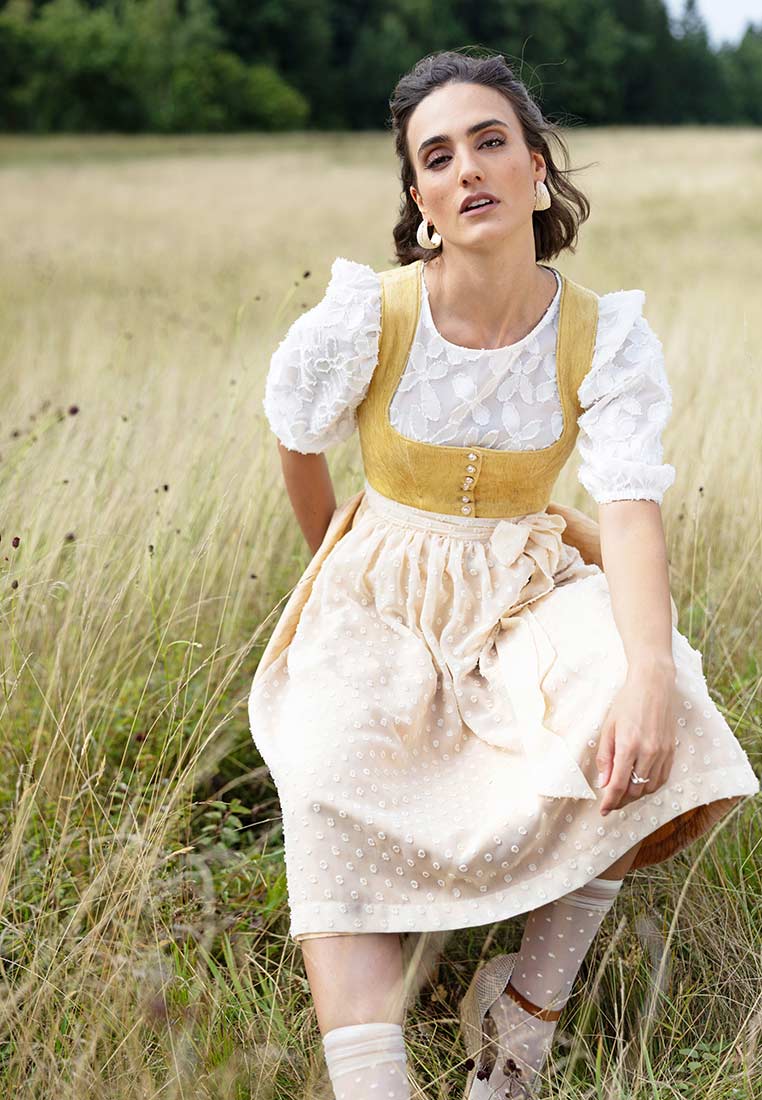 Frontansicht des Marjo Dirndl Wolfersdorf in Safrangelb mit hellbeiger Trachtenrock und weißer Bluse. Das Dirndl ist kurz geschnitten.