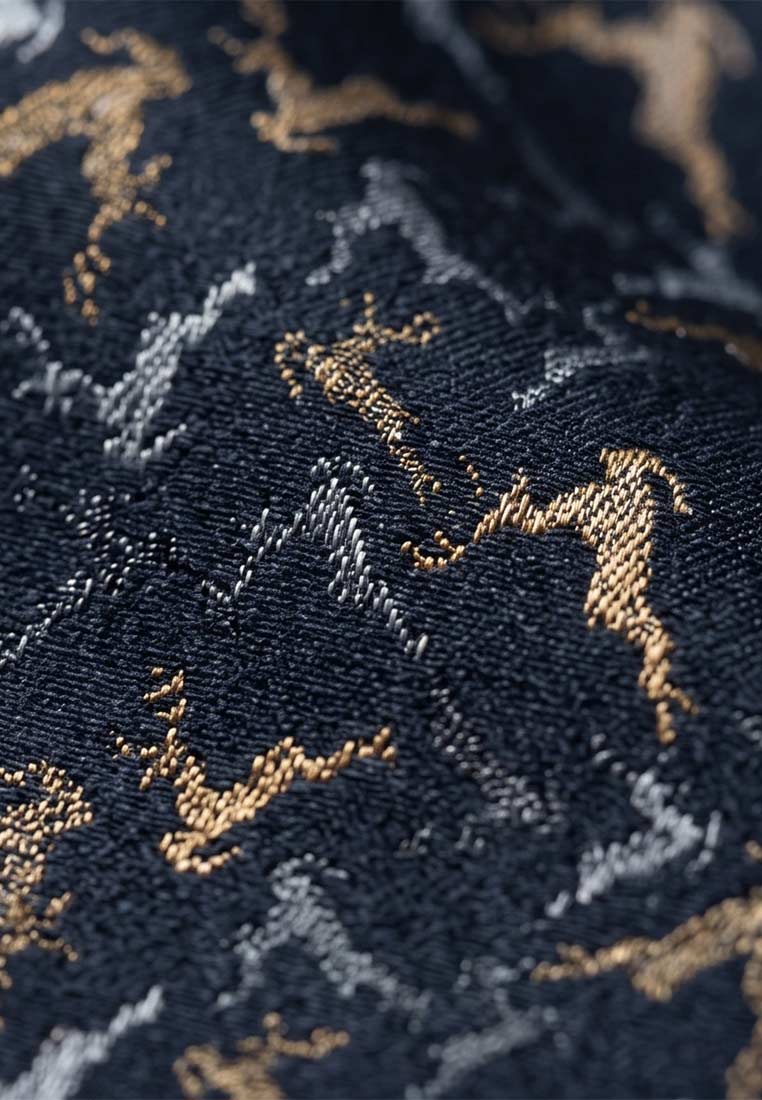 Detailansicht des Stecktuchs kleine Hirsche marine von Luise Steiner. Das marineblaue Stecktuch zeigt ein eingewebtes Muster aus kleinen Hirschen in Gold- und Silbertönen.