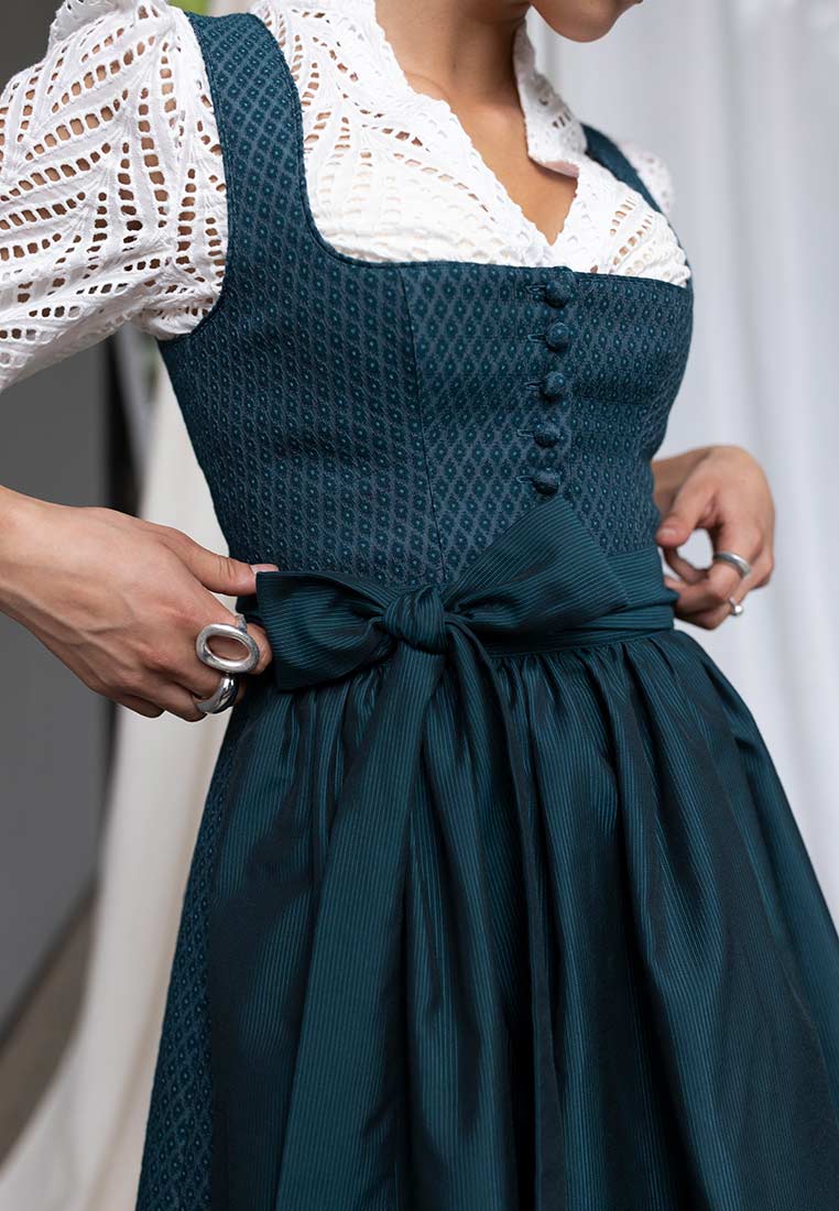 Madame Marie Dirndlbluse Norelin weiss, Frontansicht. Die Bluse ist aus weißer Spitze mit Puffärmeln und einem geschlossenen Kragen gefertigt.
