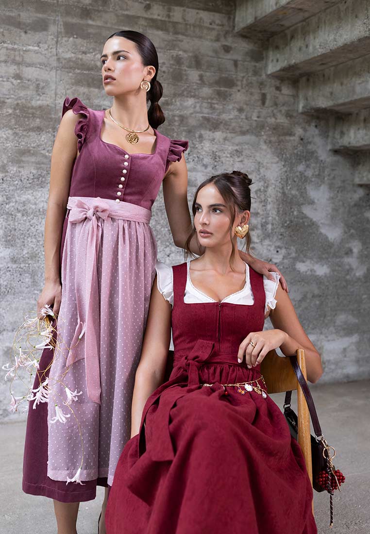 Madame Marie Dirndl Soralyn Samt pflaume (borderaux) 65 cm: Frontansicht eines pflaumefarbenen Samtdirndls mit rüschenbesetzten Trägern und einer hellrosa Schürze mit Tupfenmuster.