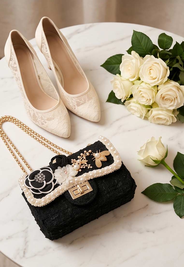 Schmuckzauber Tweed Trachtentasche Glamour schwarz Goldtraum, Frontansicht. Die schwarze Tasche hat eine goldene Kette und eine Perlenverzierung am Rand.