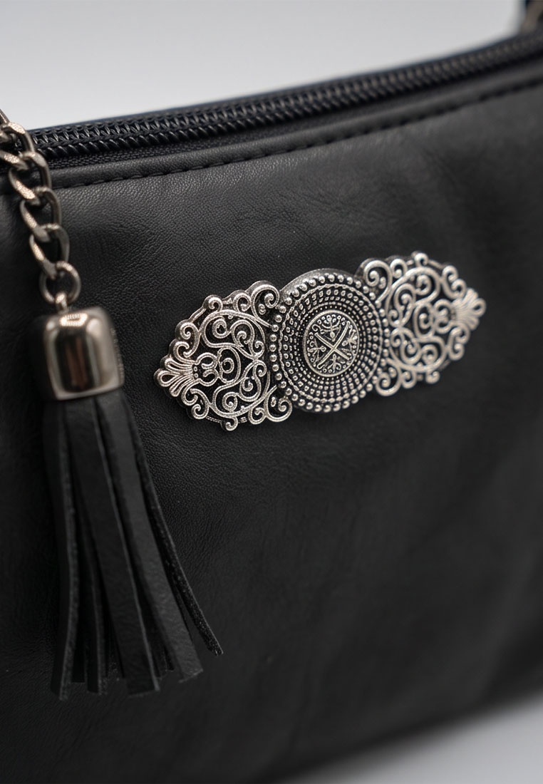 Detailaufnahme einer schwarzen Trachtentasche Marie von Taschenzauber mit einem Zieranhänger und einem Quastenanhänger aus Leder.