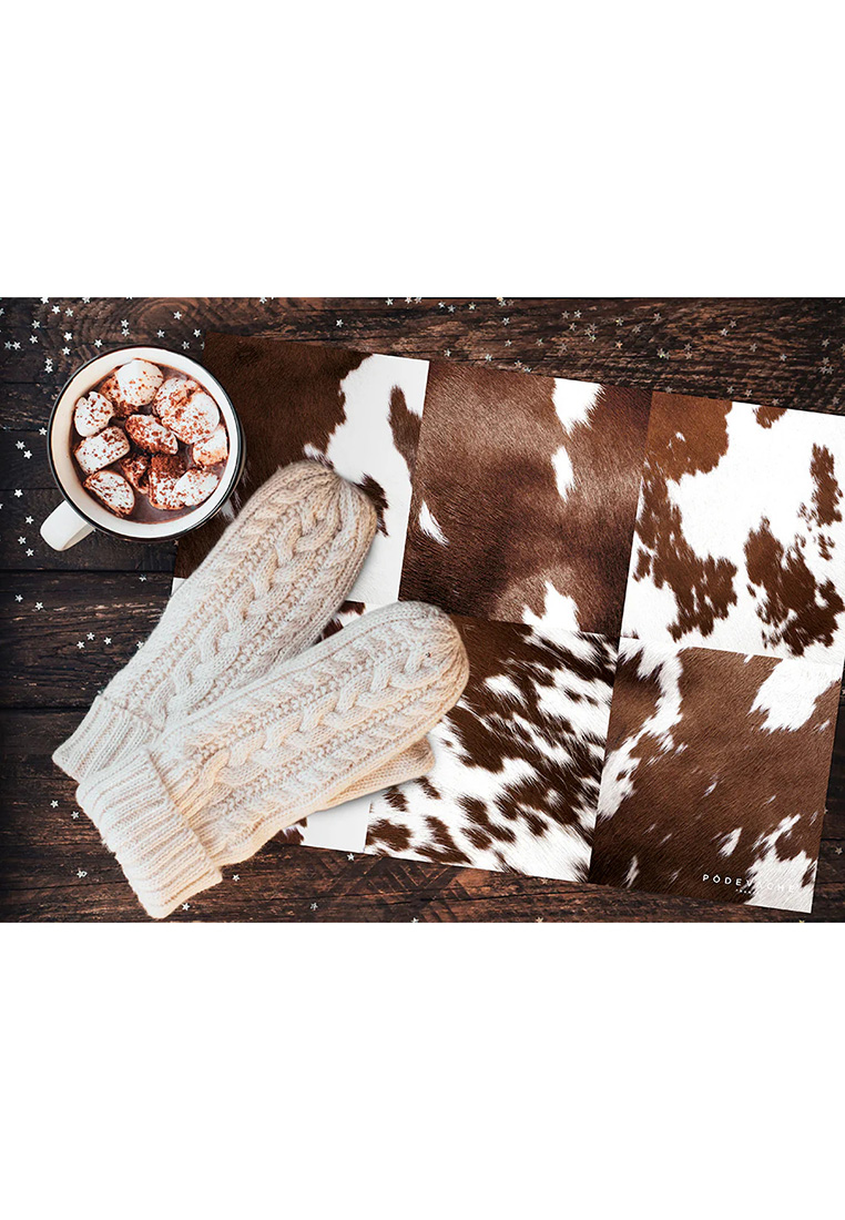 Pôdevache Vinyl Tischset Kuh 6er Set in Braun-Weiss, Stimmungsbild auf Holztisch, dekoratives Kuhfell-Muster für Chalet Chic Ambiente.