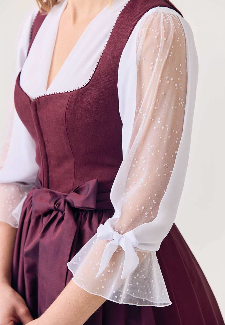 Waldorff Dirndlbluse Emilia in Weiss, Frontansicht, mit weissen Punkten auf den Ärmeln und Schleifen am Bund und Ärmelsaum. Klassische Tracht.