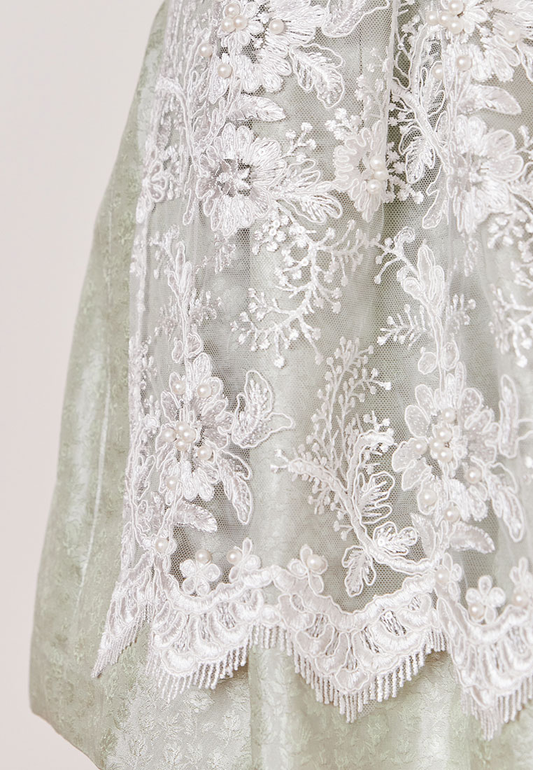 Krüger Dirndl Zephyra hellgrün – Frontansicht eines hellgrünen Dirndls mit weißer Spitze und Perlenverzierungen. Deutlich erkennbar ist der Spitzensaum.
