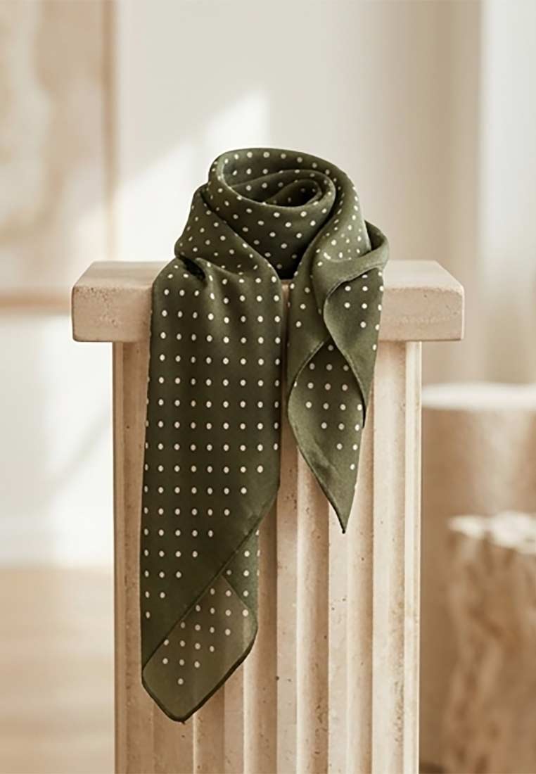 Schmuckzauber Nickituch Pünktchen olive, eine Frontansicht eines stilvollen Seidentuchs mit kleinen weißen Punkten und einer eleganten Olivgrün-Farbe, drapiert.