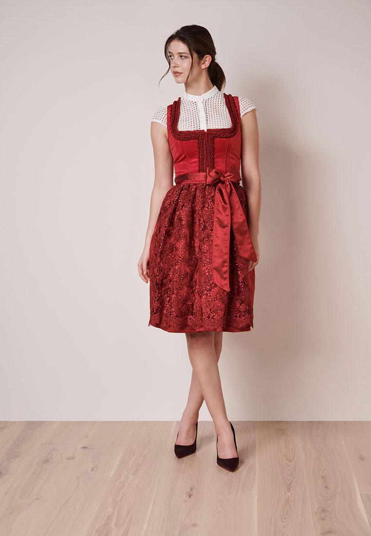 Krüger Dirndl Elma rot: Frontansicht eines roten Dirndls mit einem satinierten Schärpenband in der Taille und einem Spitzenrock.