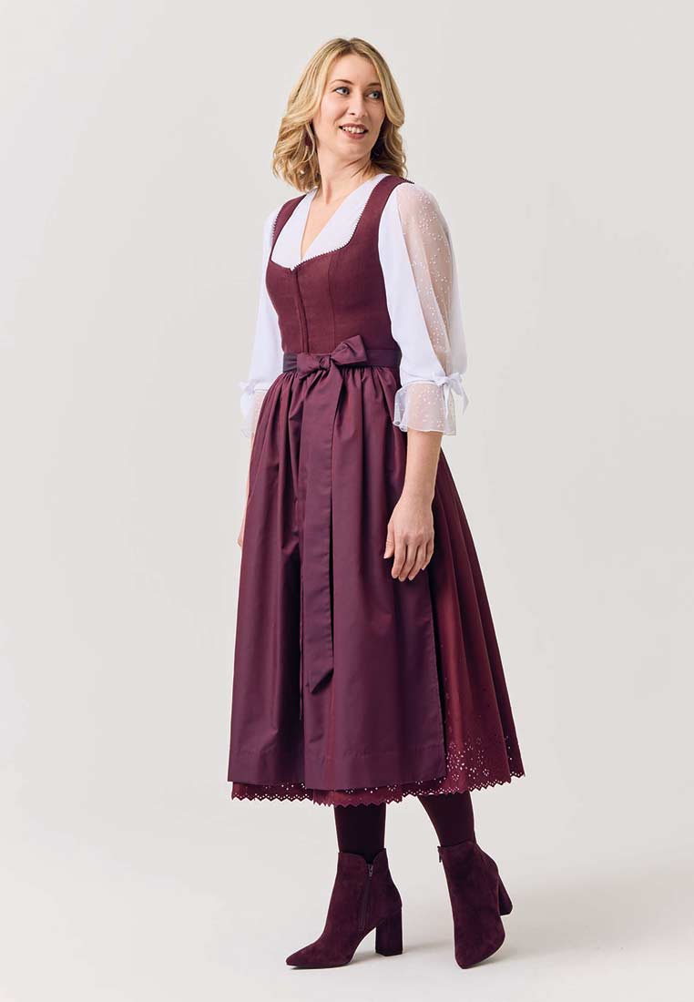 Waldorff Dirndlbluse Emilia weiss im Profil, weiss mit Puffärmeln und V-Ausschnitt, kombiniert mit einem dunkelroten Dirndl.