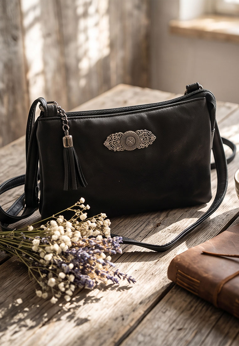 Taschenzauber Trachtentasche Marie schwarz, Frontansicht. Elegante schwarze Umhängetasche mit Reissverschluss und dekorativem Anhänger.
