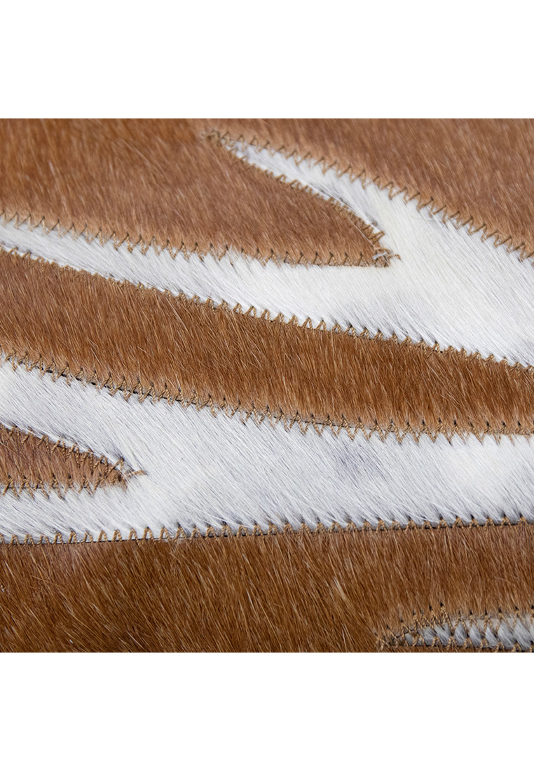 Mars&More Kissen Kuhfell braun mit Geweih 45x45cm: Detailaufnahme eines Patchwork-Kissenbezugs aus braunem und weißem Kuhfell mit sichtbaren Nähten.