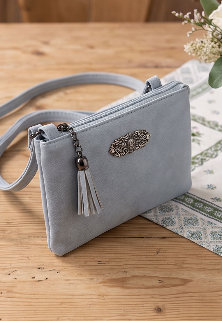 Taschenzauber Trachtentasche Marie hellblau, Frontansicht einer eleganten hellblauen Tasche mit Reißverschluss und einem Quastenanhänger.