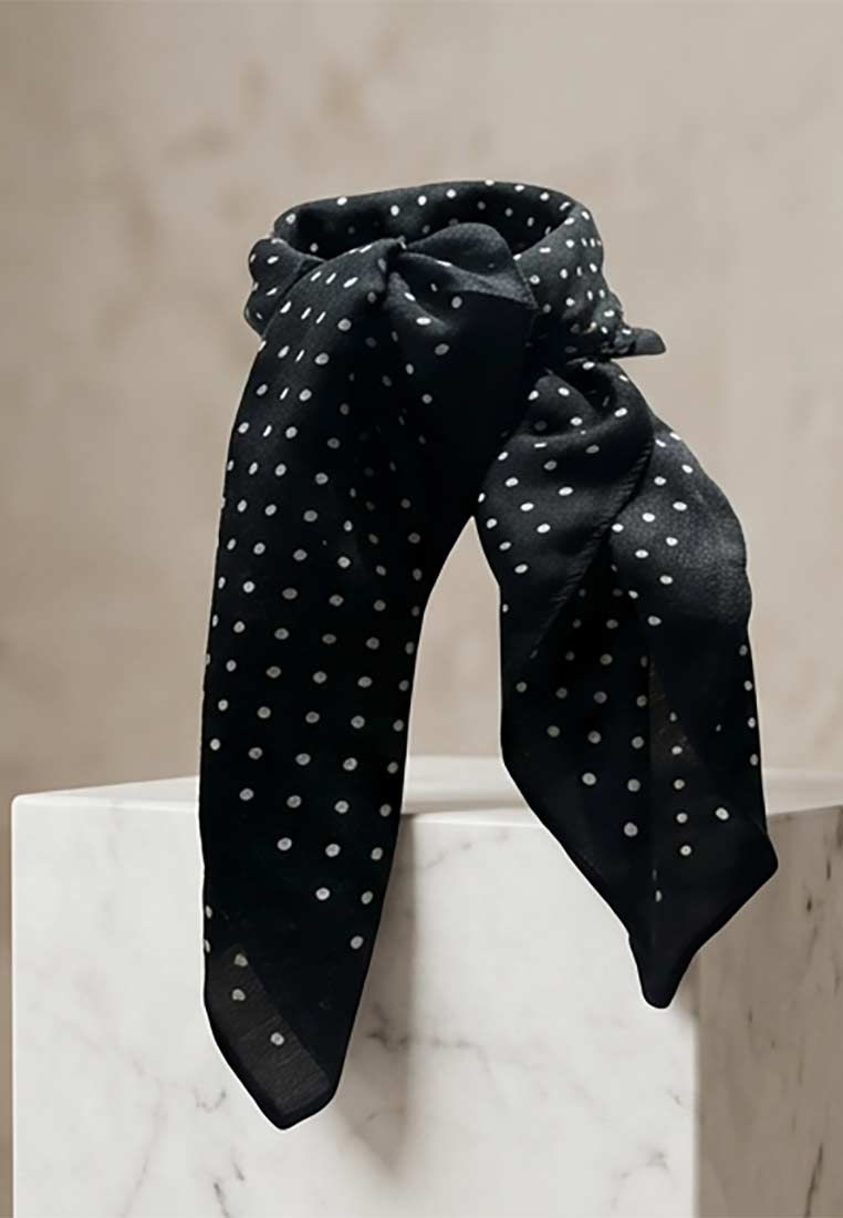 Schmuckzauber Nickituch Pünktchen schwarz aus der Frontansicht, mit einem eleganten Pünktchenmuster und einem stilvollen Knoten.
