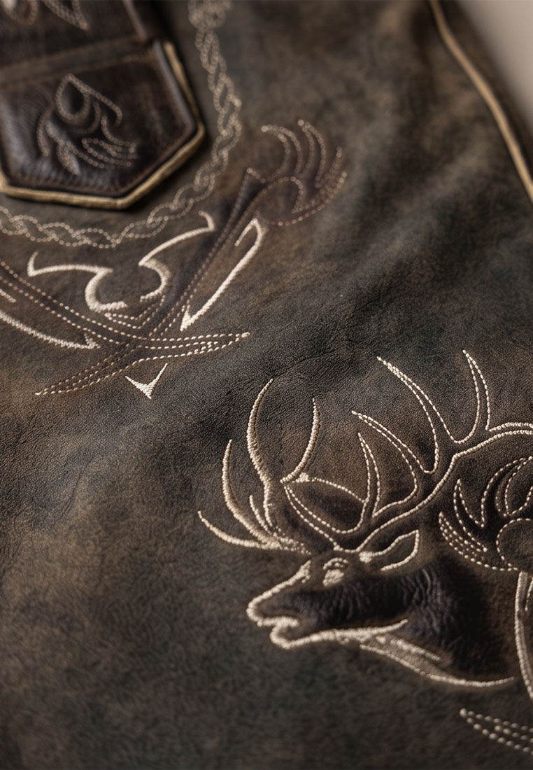 Detailansicht der Maddox Lederhose Urgsee in coffee mit Hirschstickerei und Leder-Tasche.