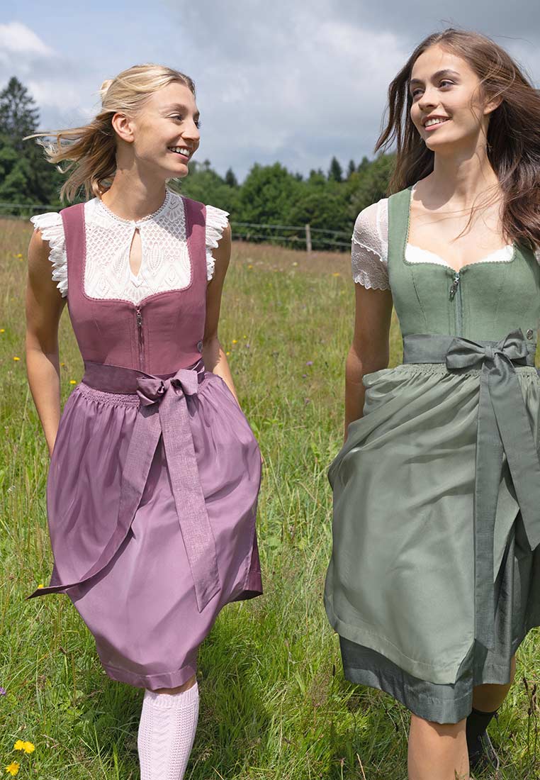 Zwei Frauen in Tracht: Marjo Dirndl Lichtenfels malve (borderaux) mit Schnürung und Marjo Dirndl in Oliv. Frontansicht.