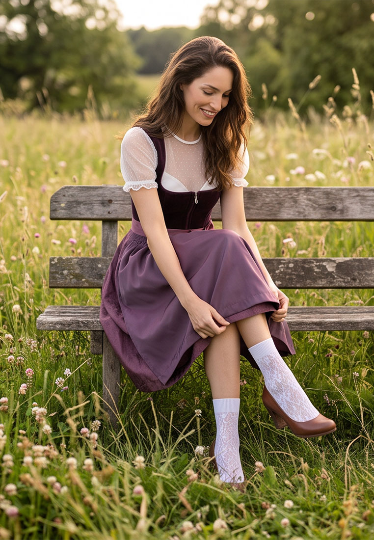 MarJo Trachten Dirndl Bidingen 70cm in pflaume. Frontansicht einer sitzenden Frau auf einer Holzbank mit detailreichem Reißverschluss vorne.
