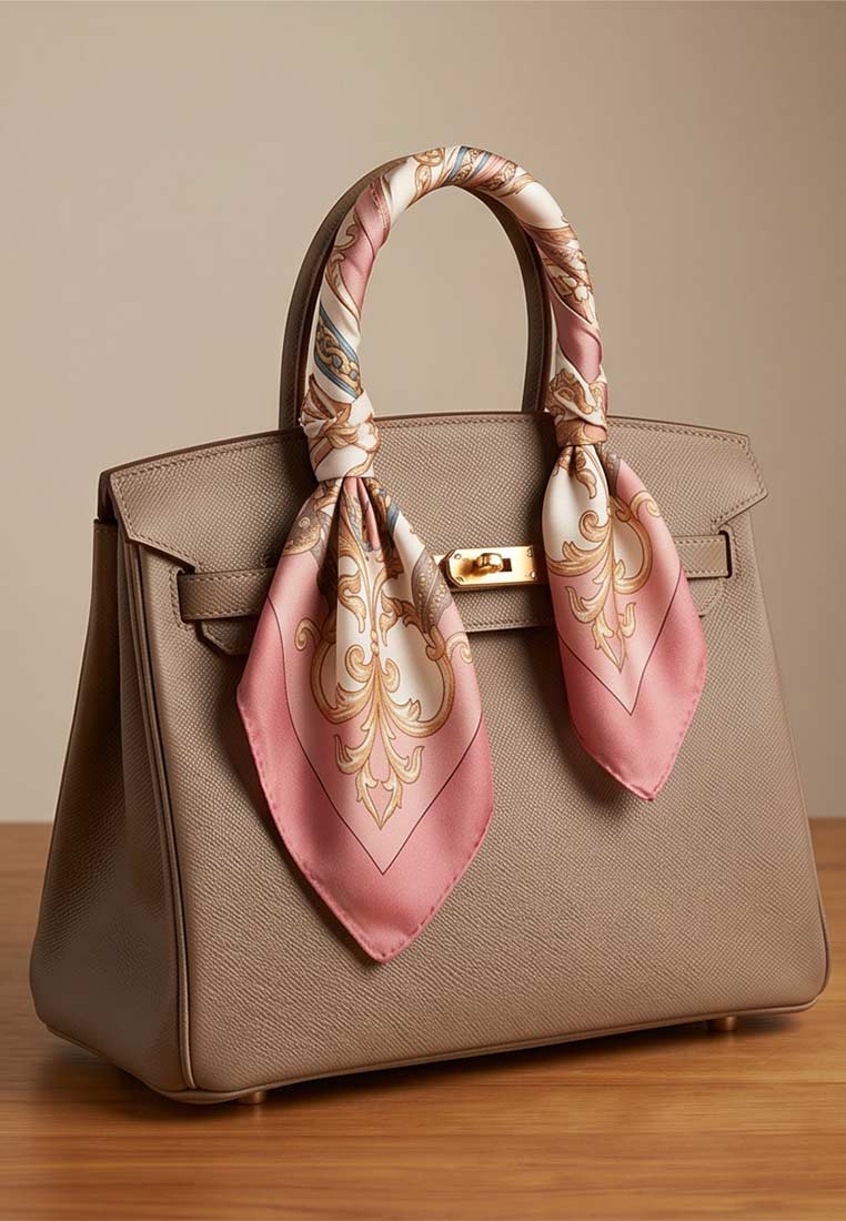 Schmuckzauber Nickituch Chains rosa im Front-Detail mit rosa und cremefarbenem Muster um die Henkel einer grauen Tasche gebunden.
