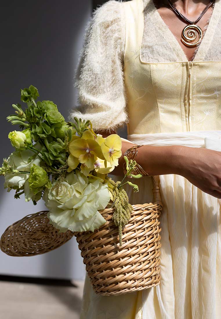 Madame Marie Dirndlbluse Kühbach gelb in Frontansicht mit Reißverschluss und quadratischem Ausschnitt, getragen mit einer Strickjacke.