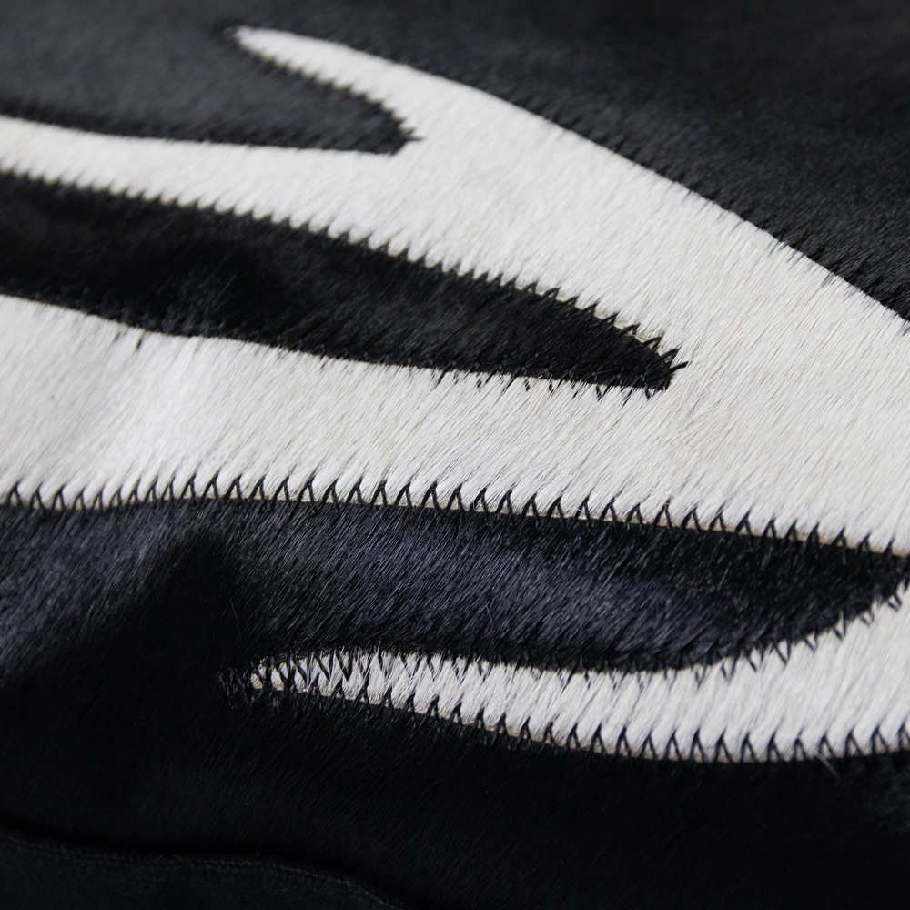 Mars&More Kissen Kuhfell schwarz mit Geweih 45x45cm: Detailansicht des schwarzen und weissen Kuhfellkissens mit sichtbarer Naht.