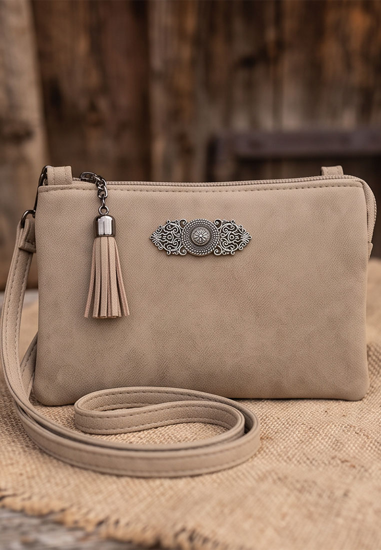 Taschenzauber Trachtentasche Marie beige Frontansicht mit Quasten und Metallapplikation, ein verstellbarer Schulterriemen ist sichtbar.
