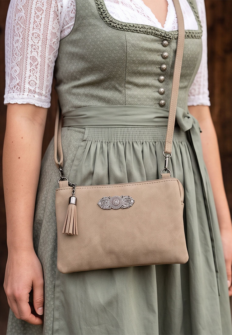 Taschenzauber Trachtentasche Marie beige, Frontansicht. Elegante Trachtentasche aus beigem Kunstleder mit einem auffälligen Anhänger und einem separaten kleineren Metallanhänger vorne.