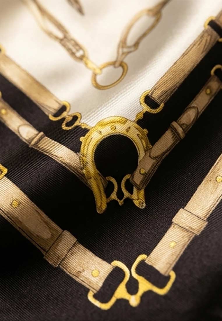 Detailaufnahme des Schmuckzauber Nickituchs Timeless in Schwarz mit einem goldenen Hufeisenmotiv und Schnallenmuster.