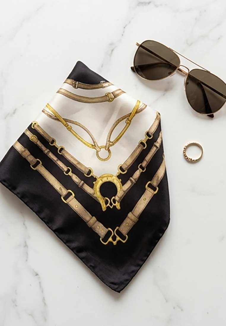 Schmuckzauber Nickituch Timeless schwarz, Frontansicht mit Schnallen- und Steigbügelmotiv in Creme und Gold auf schwarzem Grund.