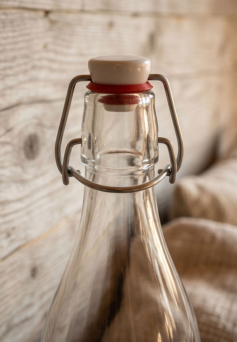 TRENDFORM Glasflasche 1L SWISS TRADITION: Frontansicht einer klaren Glasflasche mit Bügelverschluss und rotem Dichtungsring.