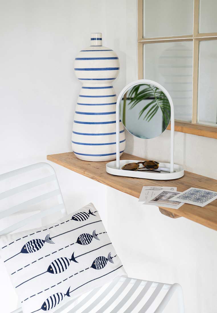 J-LINE Kissen Fisch weiss blau: Frontansicht eines weißen Kissens mit blauem Fischmuster und horizontalen Linien auf einer gestreiften Liege.