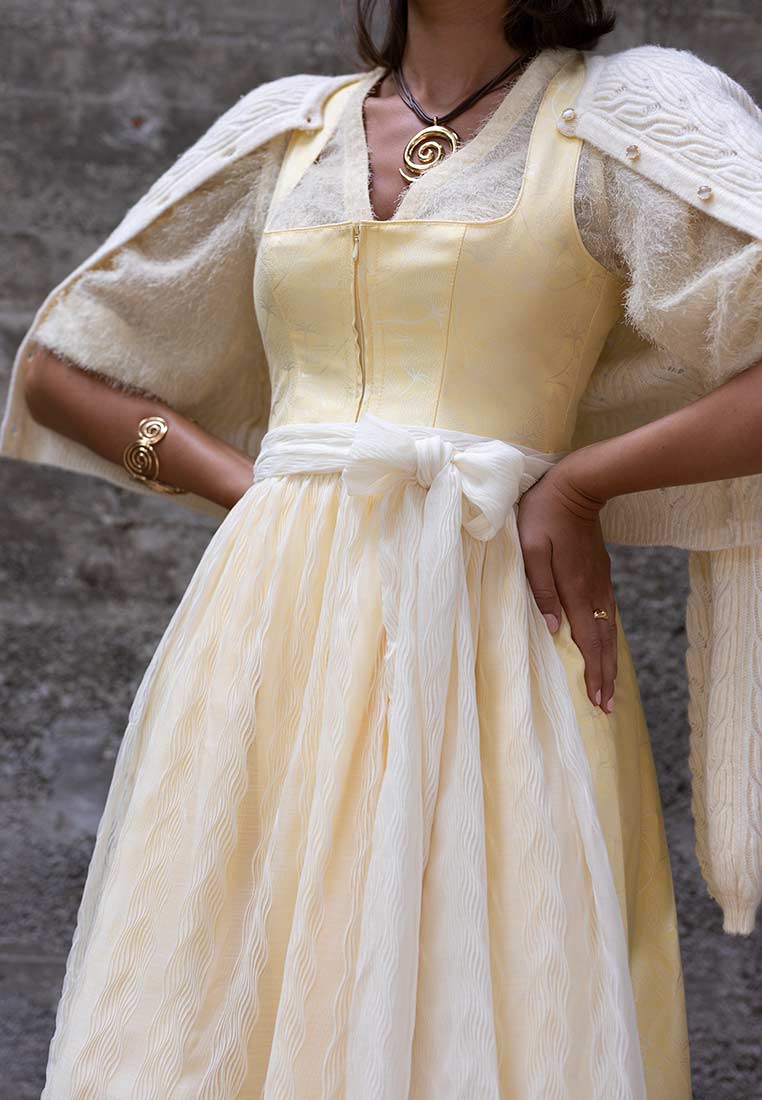 Madame Marie Trachtenstrickjacke Avenara cremeweiss, Frontansicht. Elegante cremeweiße Strickjacke mit Zopfmuster und leicht flauschigem Besatz an den Ärmeln.