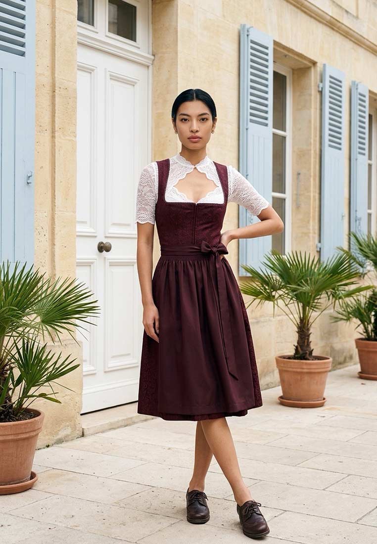Trachten Deiser Dirndl Babsi in Bordeaux 60 cm, Frontansicht. Das elegante Dirndl mit weißer Spitzenbluse hat einen gebundenen Gürtel und eine schwingende Rockpartie.