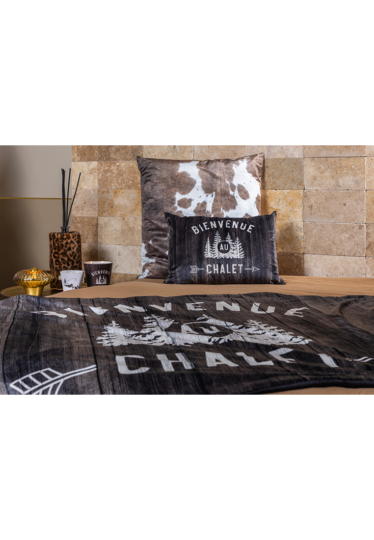 Podevache Kissen Chalet Chic 40x60cm in dunklem Braun mit weisser Schrift, Frontansicht. Das Kissen zeigt einen Holzmusterdruck mit Schriftzug und Bäumen.